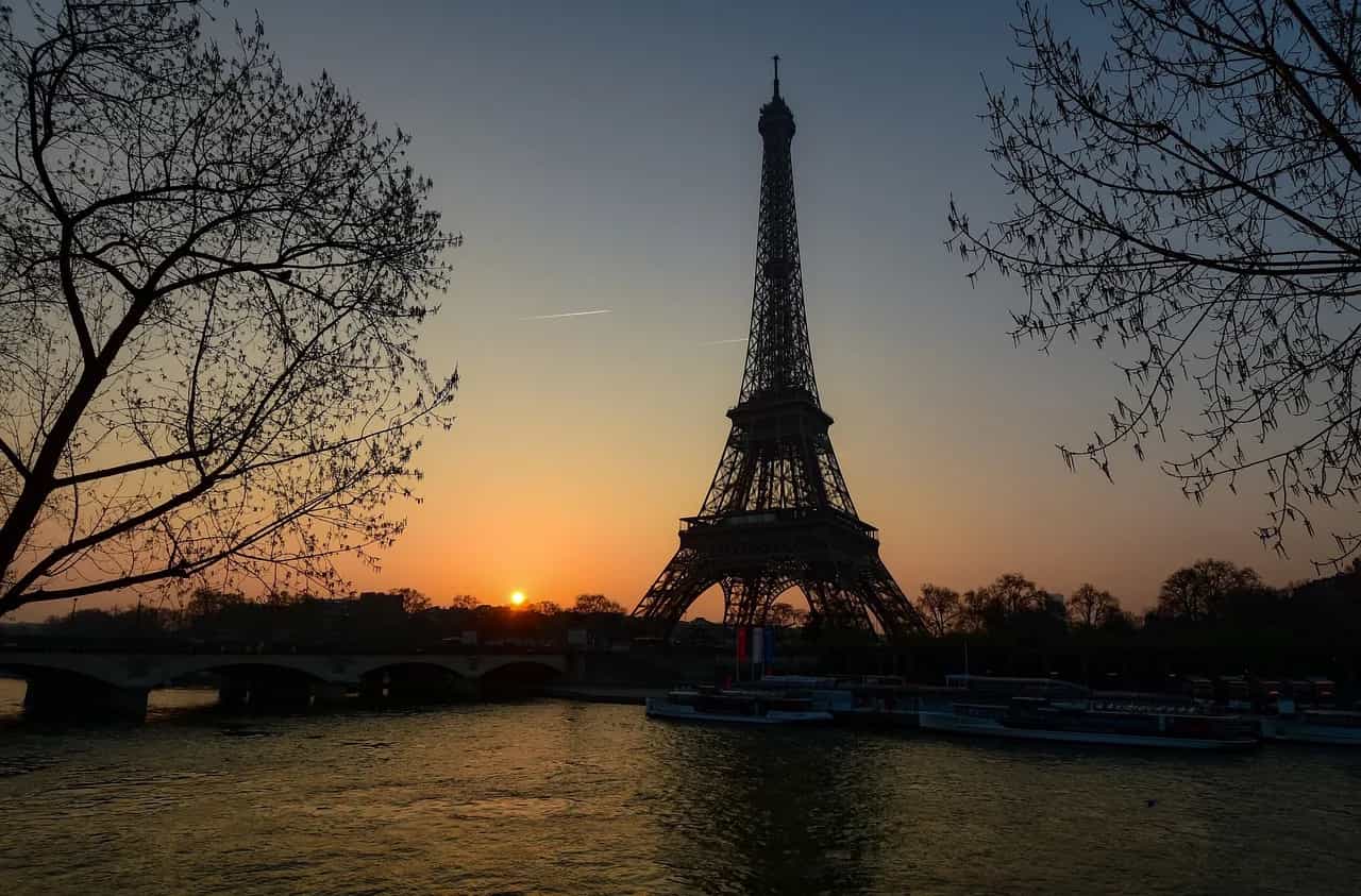 Kulla Eifel në lindje të diellit mbi Senë, Paris, Francë – siluetë e kornizuar nga pemet buzë lumit