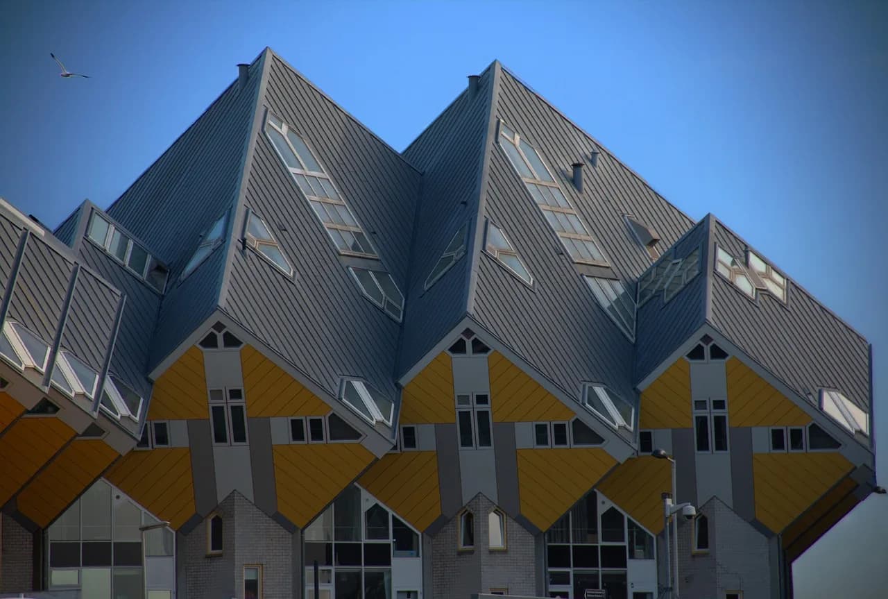 The tilted yellow and grey Cube Houses of Rotterdam against a blue sky.