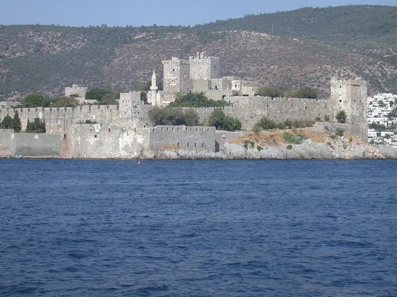 The stone walls and towers of Bodrum Castle rising above the dark blue Aegean.