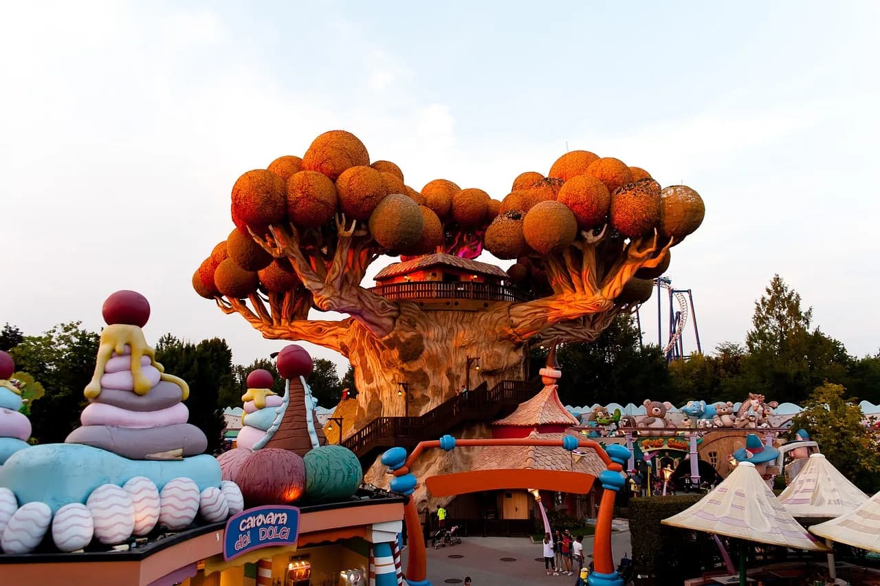 Colourful rides and the big themed tree rising above the paths of Gardaland theme park.