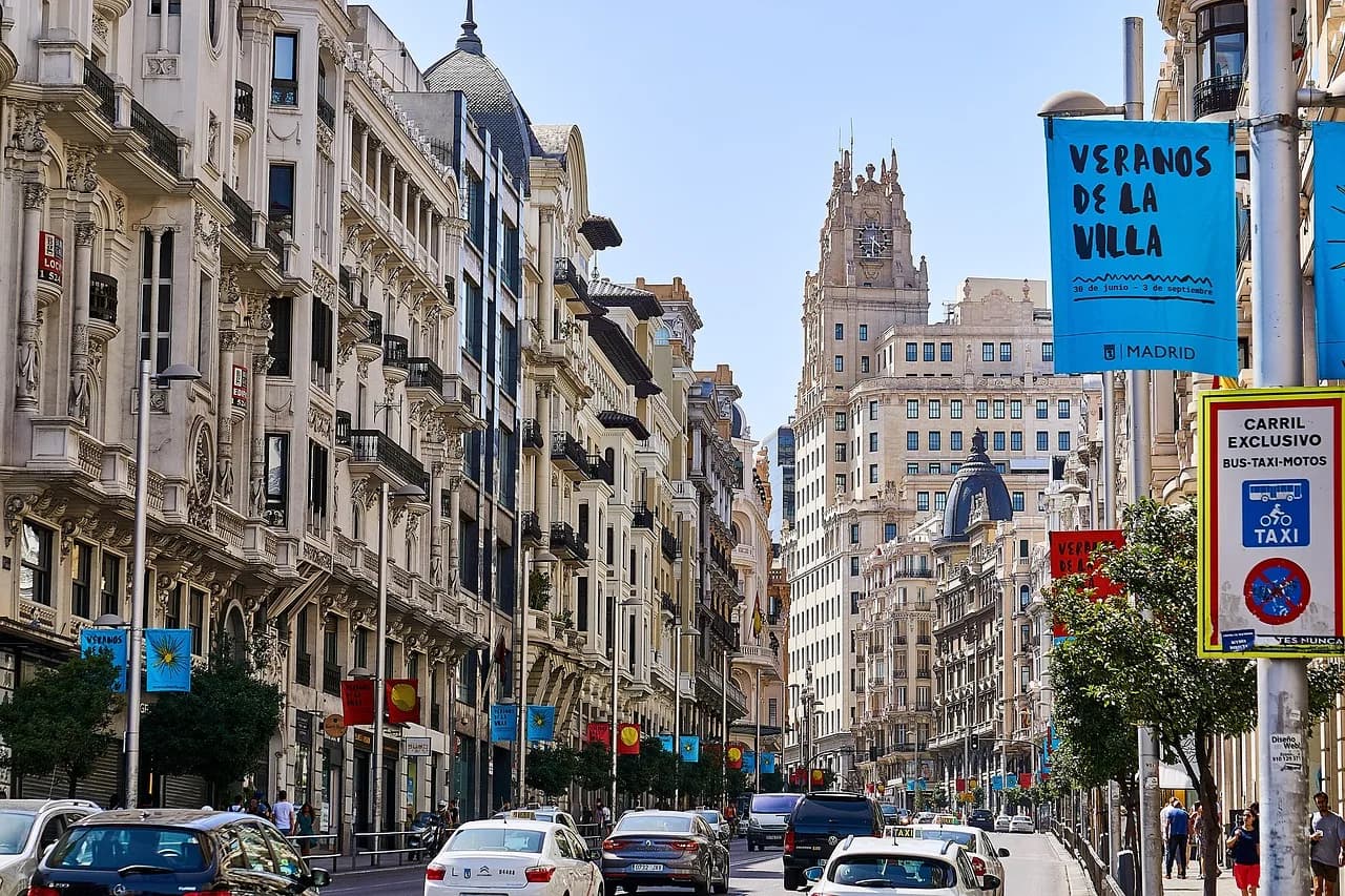 Belle Époque buildings lining the Gran Vía in Madrid on a sunny day, with traffic below.