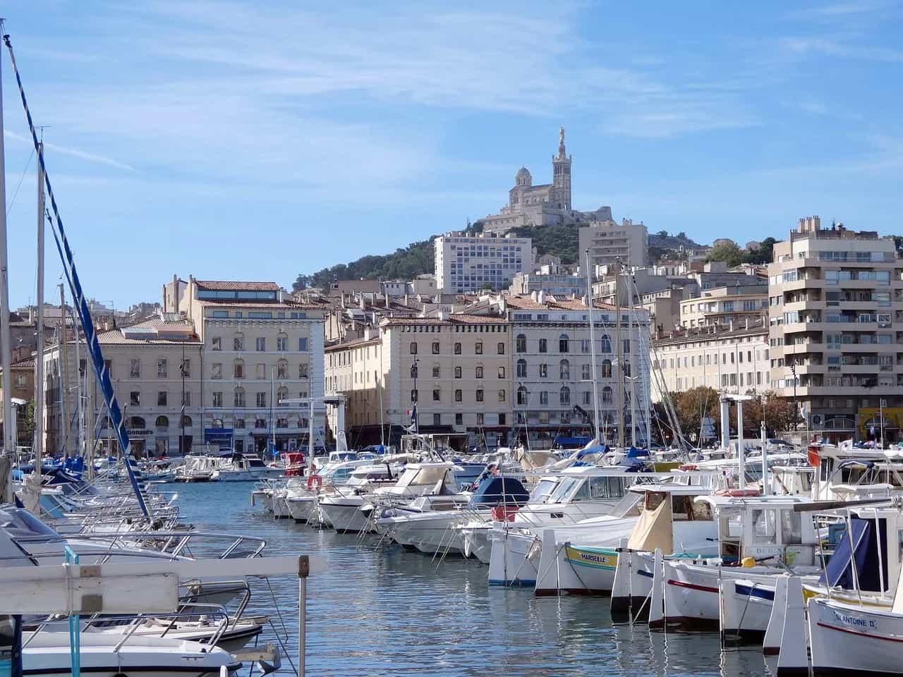 The Vieux-Port of Marseille with moored boats and the basilica of Notre-Dame de la Garde on the hill above.