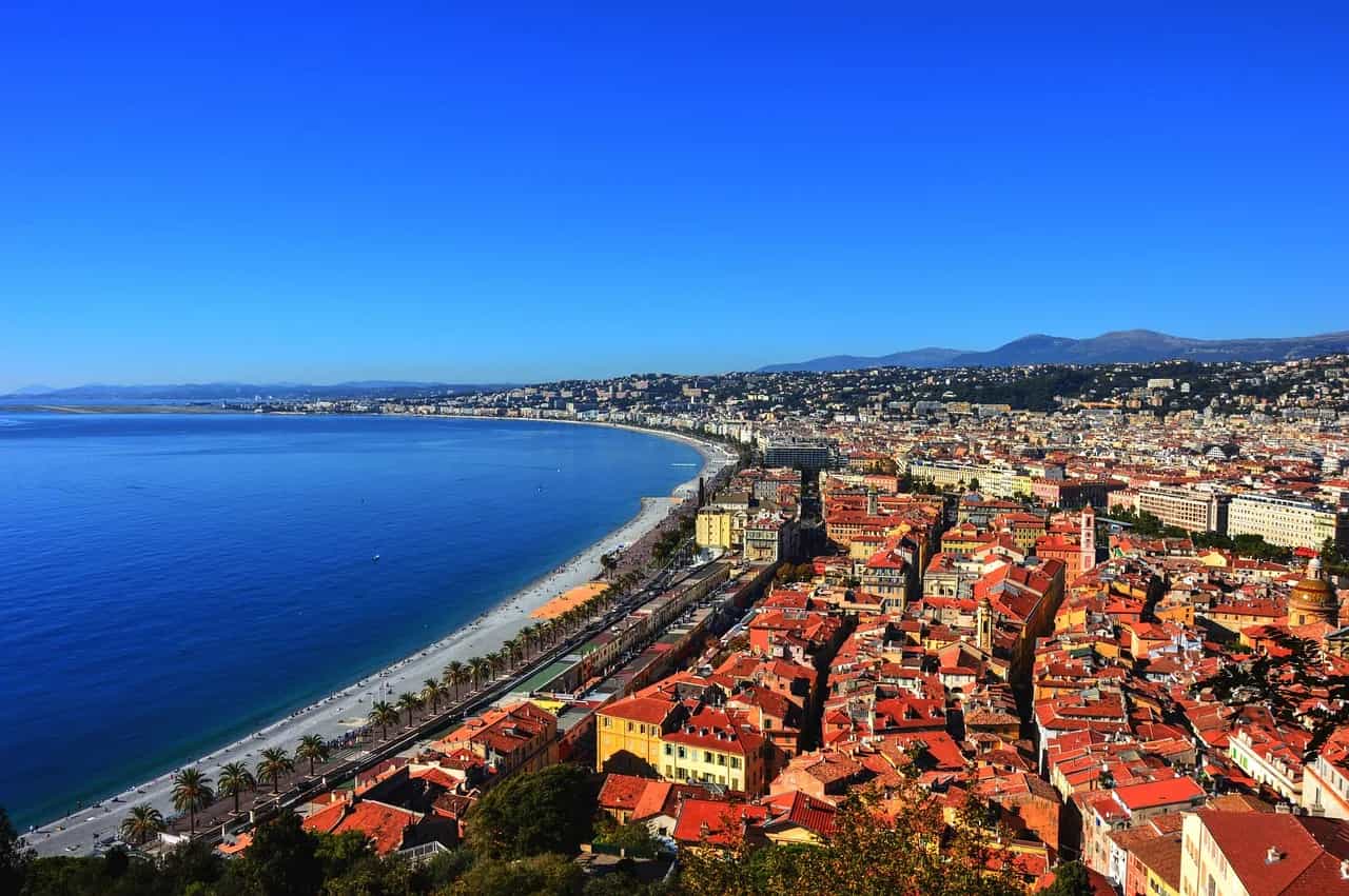 The curve of the Baie des Anges and the Promenade des Anglais seen from above, with the red roofs of Nice below.