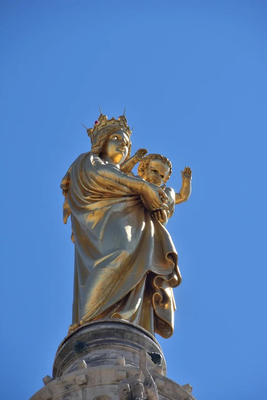 The golden statue of the Virgin and Child on top of Notre-Dame de la Garde against a deep blue sky.