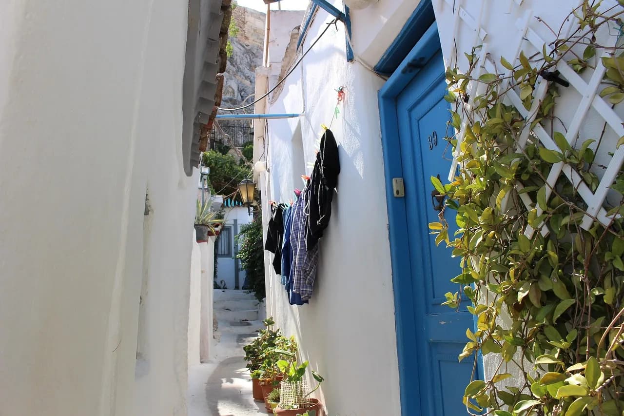 Rrugicë e ngushtë në Plaka, Athinë, Greqi – shtëpi të bardha dhe dyer blu